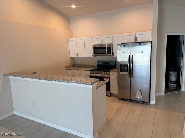 kitchen with stainless steel appliances, light stone countertops, kitchen peninsula, and white cabinets