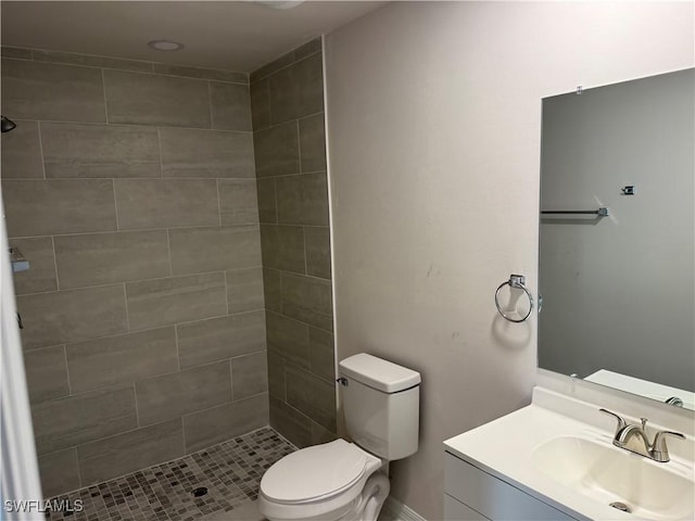 bathroom with vanity, toilet, and a tile shower