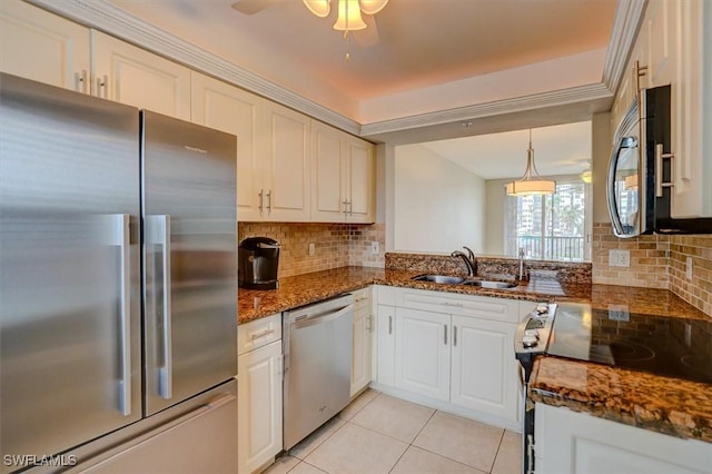 kitchen with pendant lighting, appliances with stainless steel finishes, white cabinetry, dark stone counters, and sink