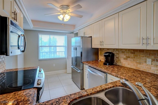 kitchen featuring appliances with stainless steel finishes, white cabinetry, dark stone counters, sink, and backsplash