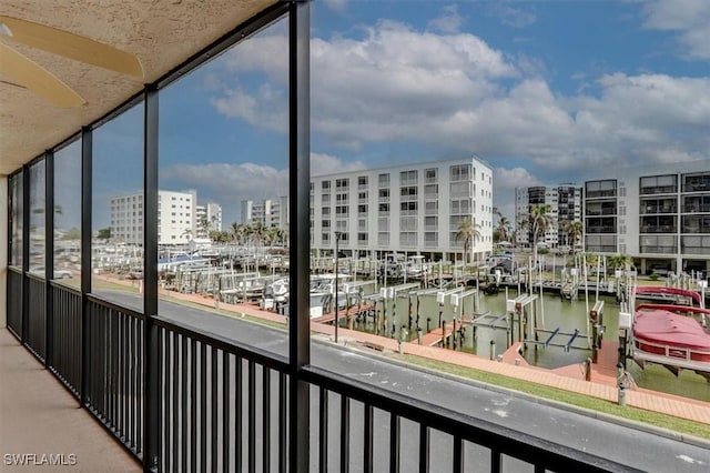 balcony with ceiling fan, a water view, and a boat dock