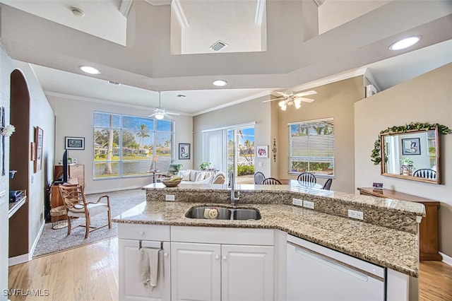 kitchen featuring dishwasher, sink, white cabinets, ornamental molding, and an island with sink