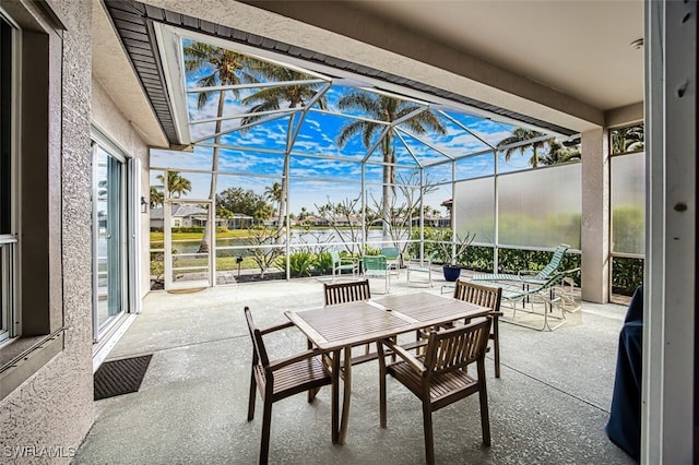 view of patio / terrace with glass enclosure, a pool, and a water view