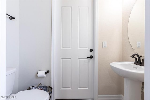 bathroom with toilet, baseboards, and a sink