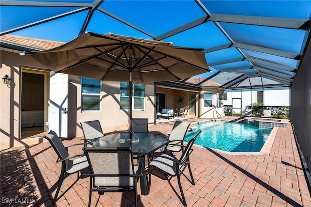 view of pool with an in ground hot tub, a patio area, and glass enclosure