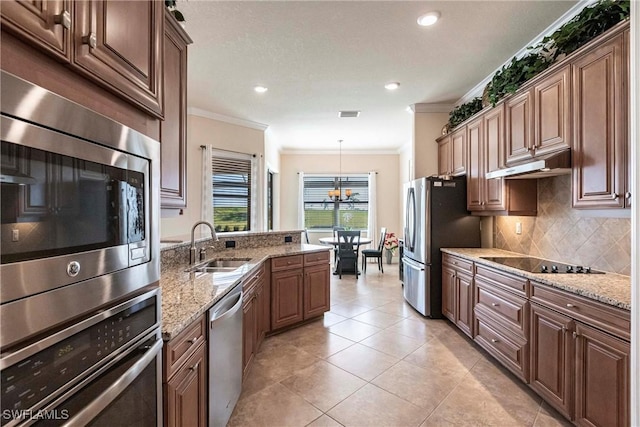 kitchen with under cabinet range hood, stainless steel appliances, ornamental molding, and a sink