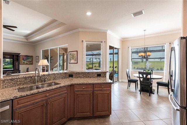 kitchen with visible vents, pendant lighting, light stone counters, stainless steel appliances, and a sink