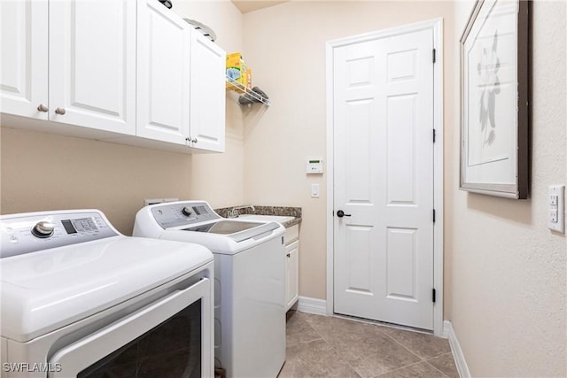 washroom featuring baseboards, light tile patterned floors, washer and dryer, cabinet space, and a sink