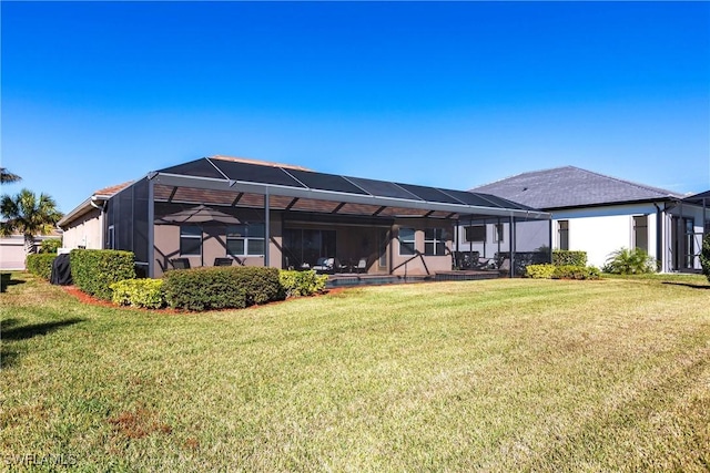 back of property with glass enclosure, a yard, and stucco siding