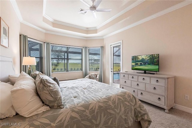 bedroom with a tray ceiling, light colored carpet, visible vents, and ornamental molding