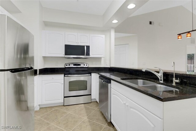 kitchen featuring dark stone countertops, sink, light tile patterned floors, stainless steel appliances, and white cabinets