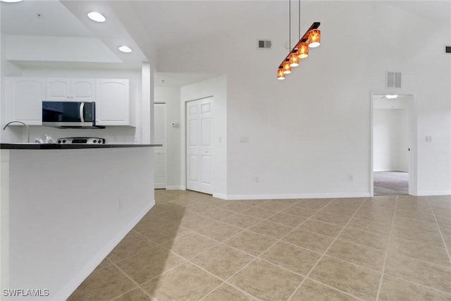 kitchen with kitchen peninsula, light tile patterned floors, white cabinets, and hanging light fixtures