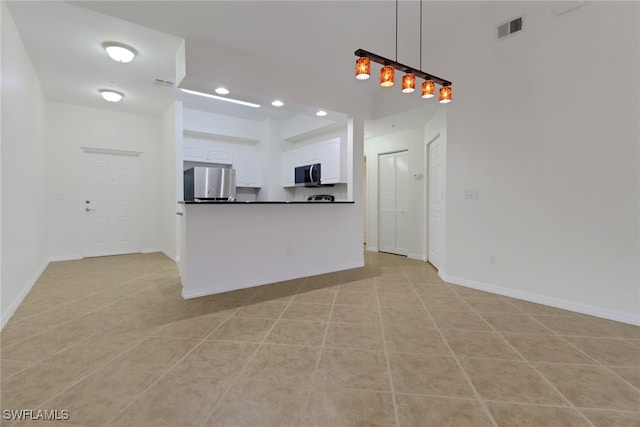 kitchen with hanging light fixtures, white cabinets, refrigerator, and light tile patterned flooring