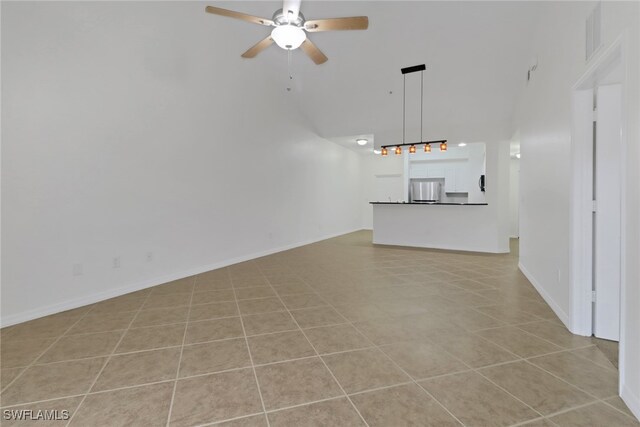 unfurnished living room with ceiling fan, light tile patterned floors, and a towering ceiling