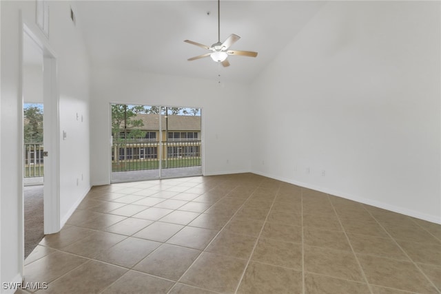 tiled empty room with ceiling fan, a towering ceiling, and plenty of natural light