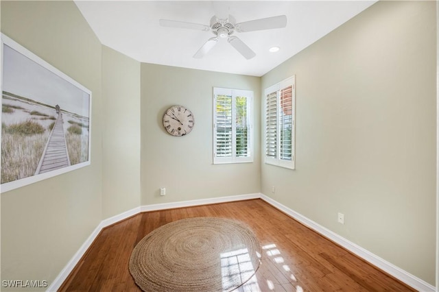 spare room with a ceiling fan, wood finished floors, and baseboards