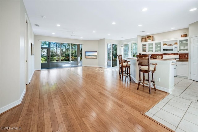 kitchen with a kitchen island, light wood-type flooring, white cabinets, and a kitchen breakfast bar