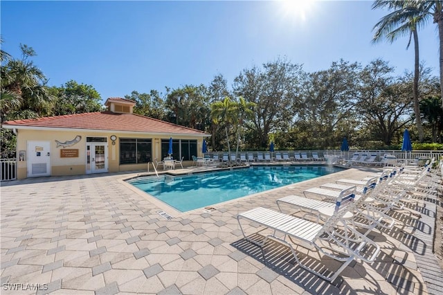 community pool with french doors, a patio, and fence