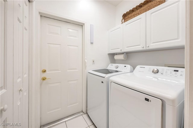 clothes washing area with cabinet space, light tile patterned floors, and washing machine and dryer