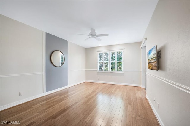 spare room featuring wood finished floors, baseboards, and ceiling fan