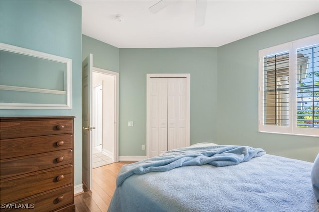 bedroom featuring a ceiling fan, wood finished floors, a closet, and baseboards