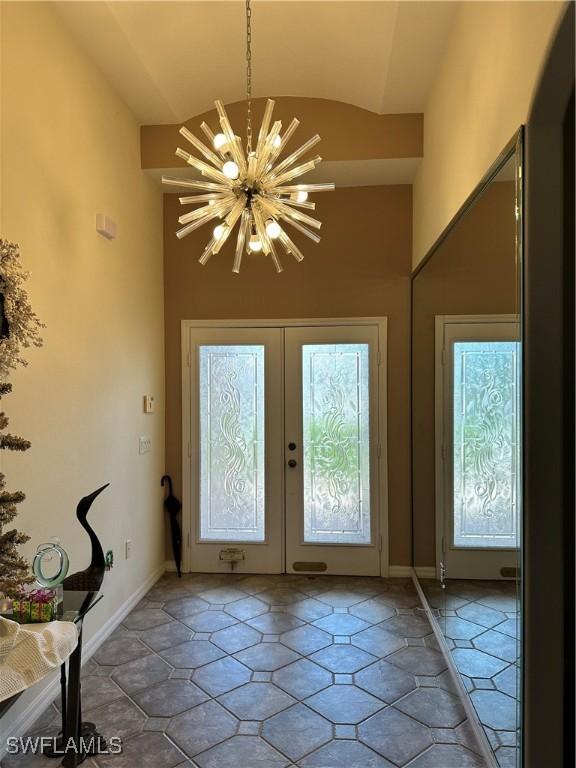 doorway to outside featuring lofted ceiling, french doors, and a notable chandelier