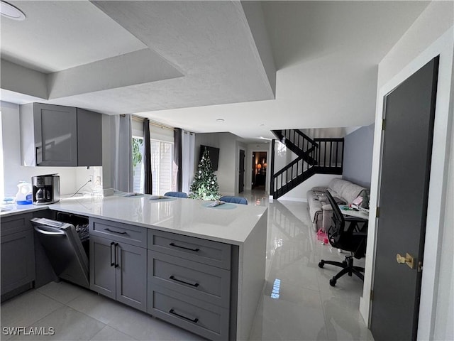 kitchen with light tile patterned flooring, built in desk, kitchen peninsula, and gray cabinets