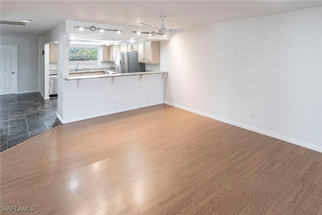 unfurnished living room featuring ceiling fan and dark wood-type flooring