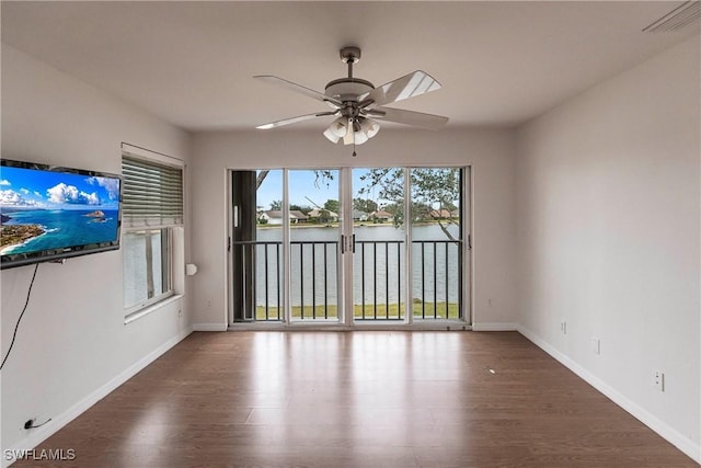 unfurnished living room with a water view, ceiling fan, and dark wood-type flooring