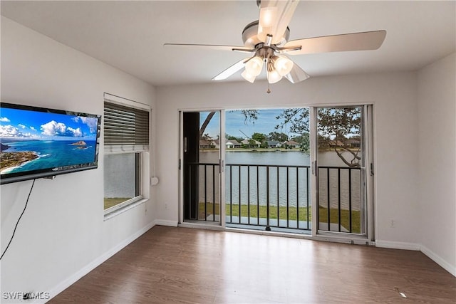 interior space featuring ceiling fan, a healthy amount of sunlight, a water view, and dark hardwood / wood-style floors