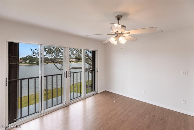 unfurnished room with ceiling fan, a wealth of natural light, and a water view