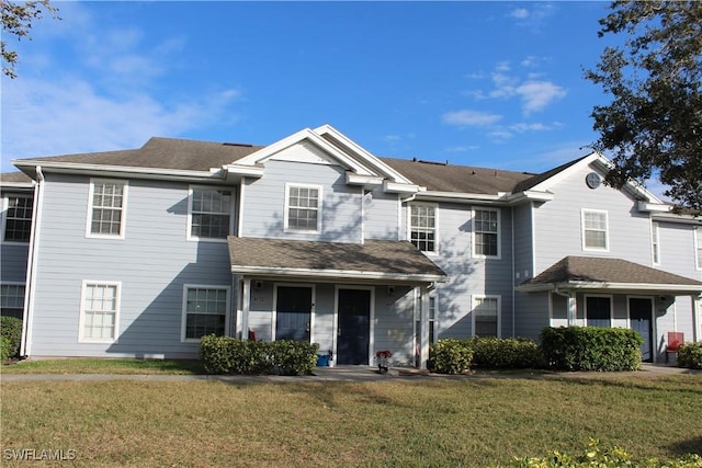 view of front of home with roof with shingles and a front yard