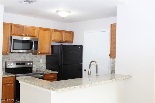 kitchen with a peninsula, a sink, appliances with stainless steel finishes, backsplash, and brown cabinetry