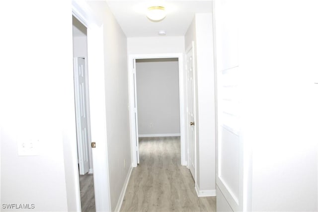 hall featuring baseboards and light wood finished floors