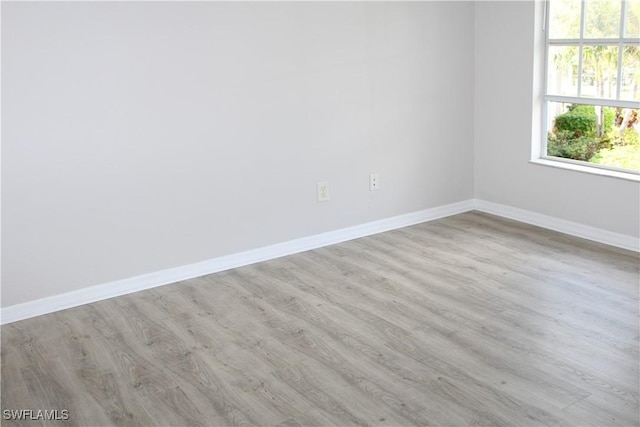 spare room featuring baseboards and wood finished floors