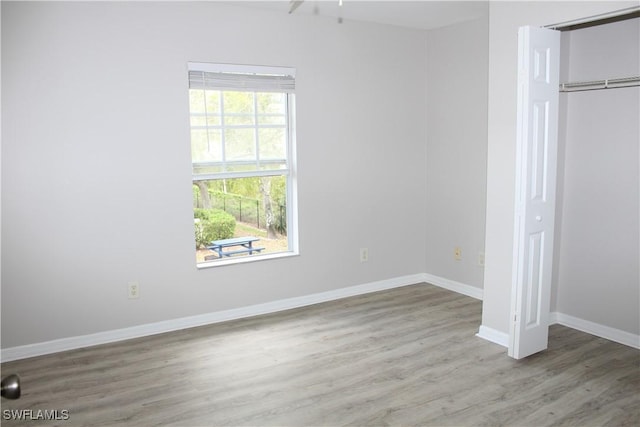 unfurnished bedroom with a closet, baseboards, and wood finished floors