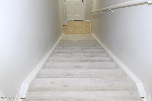 staircase featuring baseboards and wood finished floors