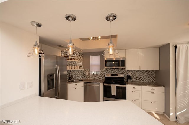 kitchen with appliances with stainless steel finishes, pendant lighting, white cabinetry, and tasteful backsplash