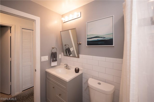 bathroom with tile walls, toilet, and vanity