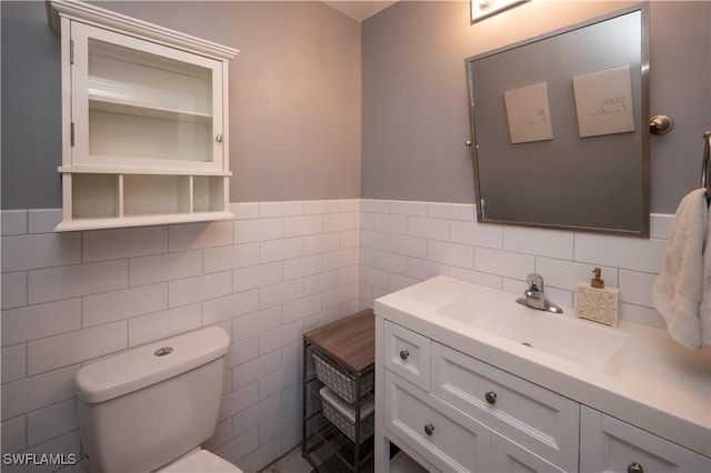 bathroom featuring toilet, vanity, and tile walls