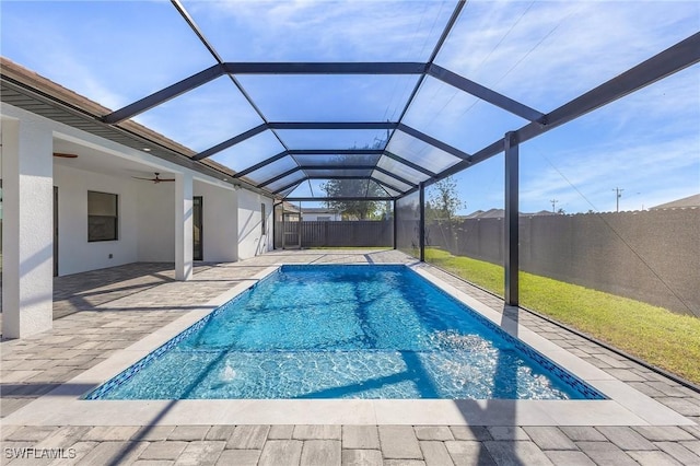 view of pool featuring glass enclosure, a patio area, and ceiling fan