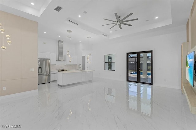 unfurnished living room featuring a raised ceiling, french doors, sink, and ceiling fan