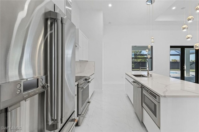 kitchen featuring appliances with stainless steel finishes, pendant lighting, a large island with sink, white cabinets, and sink