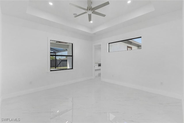 spare room with ceiling fan and a raised ceiling