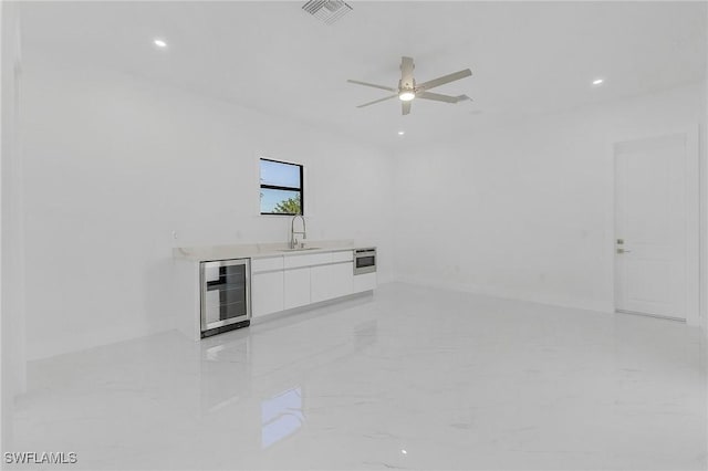 unfurnished living room featuring wine cooler, ceiling fan, and sink