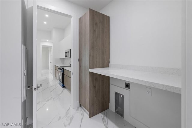 kitchen featuring built in desk, white cabinets, and stainless steel appliances