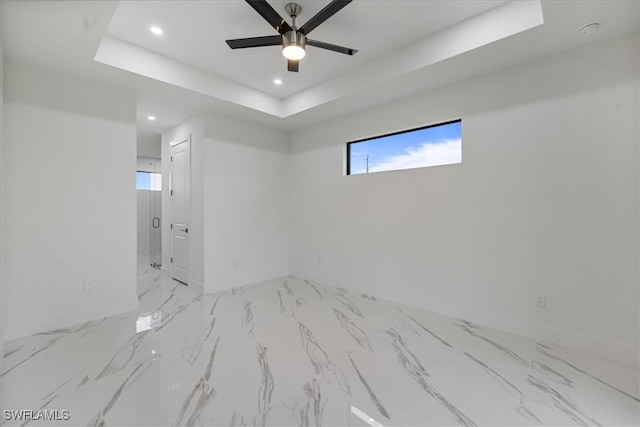 unfurnished room featuring ceiling fan and a raised ceiling