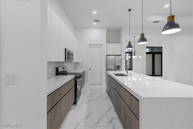 kitchen featuring decorative light fixtures, sink, white cabinetry, appliances with stainless steel finishes, and a large island