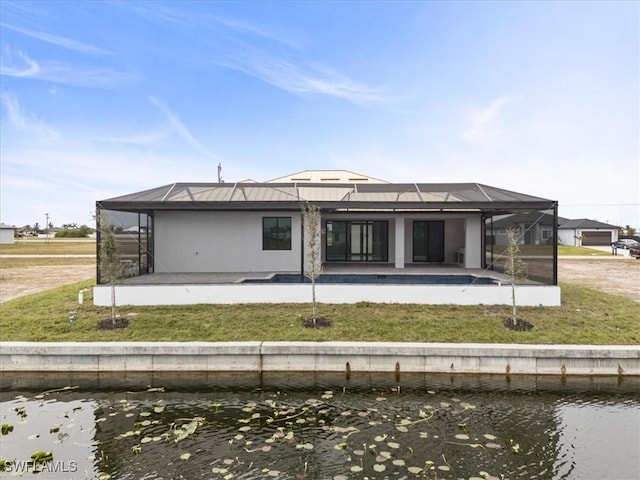 back of property with glass enclosure, a yard, a water view, and a patio