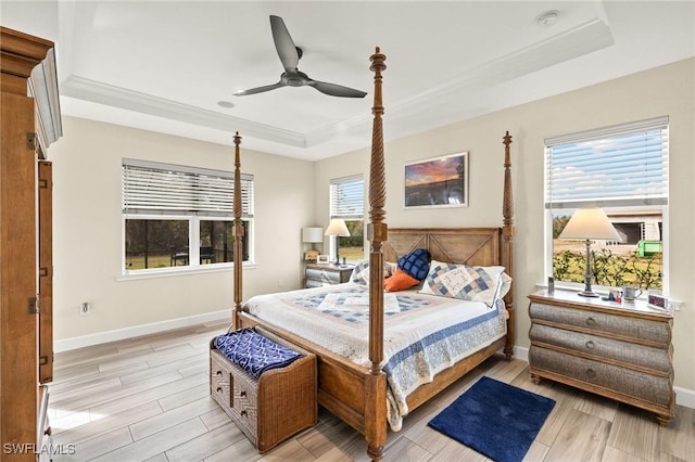 bedroom featuring multiple windows, a raised ceiling, light wood-style flooring, and baseboards